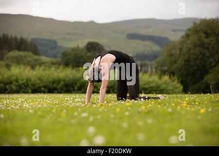 Reife Frau praktizieren Yoga nach hinten biegen im Feld Stockfoto