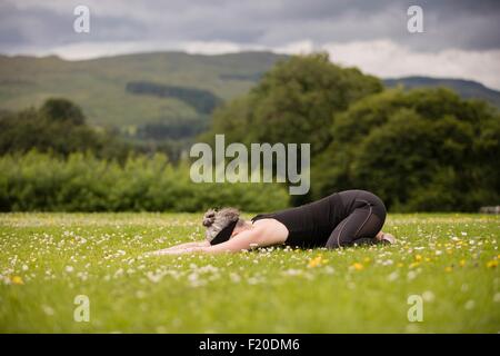 Reife Frau praktizieren Yoga Childs Position im Feld Stockfoto