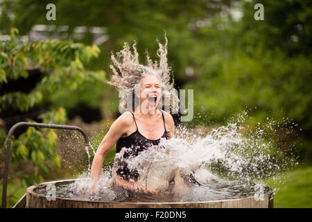 Reife Frau spritzt in frischem, kaltem Wasserwanne bei Eco retreat Stockfoto