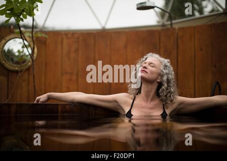 Reife Frau Entspannung im Whirlpool bei Eco retreat Stockfoto