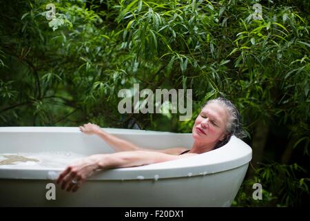 Reife Frau entspannend im Garten Schaumbad bei Eco retreat Stockfoto