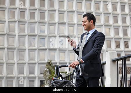 Mitte adult Business-Mann mit Fahrrad, Blick auf Smartphone Lächeln Stockfoto