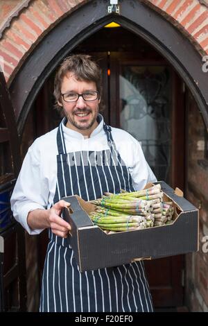 Porträt von Koch holding Box mit Spargel Stockfoto