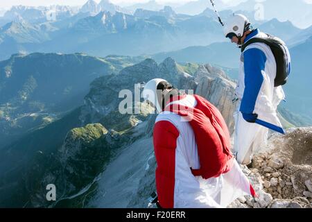 Zwei männliche BASE-Jumper stehen am Rand des Berges schaut, Dolomiten, Italien Stockfoto