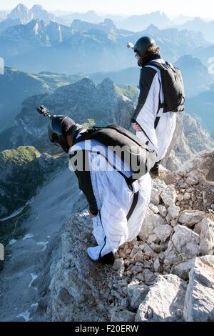 Zwei männliche BASE-Jumper vorbereiten, starten von Berg, Dolomiten, Italien Stockfoto