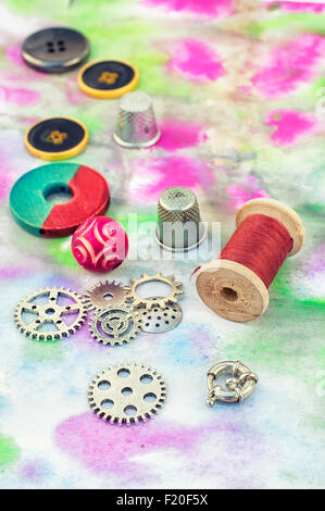 Perlen, Fäden und Beschläge auf gemalten Hintergrund gesetzt. Stockfoto