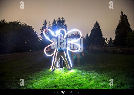 Zwei Männer stehen gemeinsam im Feld in der Dämmerung, erstellen Sternform mit Körpern, Freund Ablaufverfolgung Körperform mit Lichtspur Stockfoto