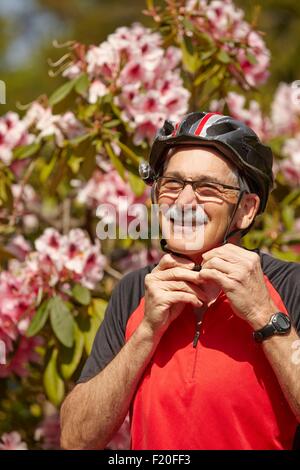 Senior woman Fahrradhelm aufsetzen Stockfoto