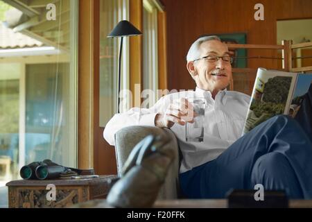 Ältere Mann zu Hause lesen Magazin Stockfoto