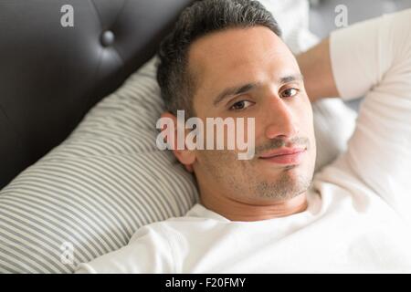 Mitte erwachsenen Mannes entspannend auf Bett Stockfoto