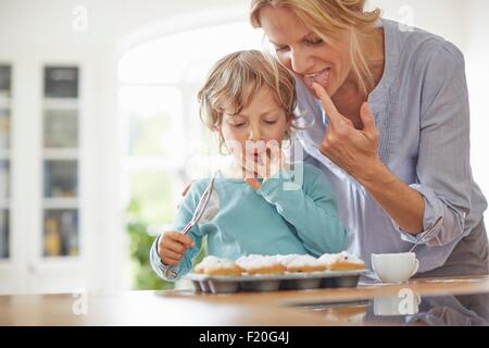 Mutter und Sohn machen Cupcakes in Küche Stockfoto