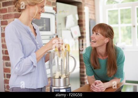 Frauen mit Mixer und chatten in Küche Stockfoto