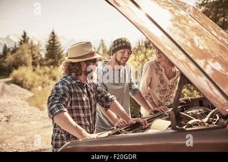 Drei Personen unter offenen Fahrzeug Haube an Motor Stockfoto