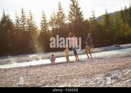 Rückansicht der Familie skimming Steinen am Fluss Stockfoto