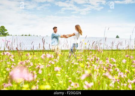 Junges Paar Hand in Hand im Feld neben Solarpark Stockfoto