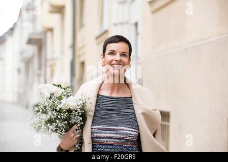 Frau mit Blumen auf Straße Stockfoto