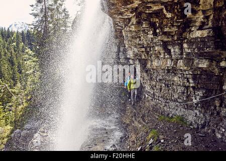 Junge Paare, die unter Wasserfall, Tirol, Österreich Stockfoto