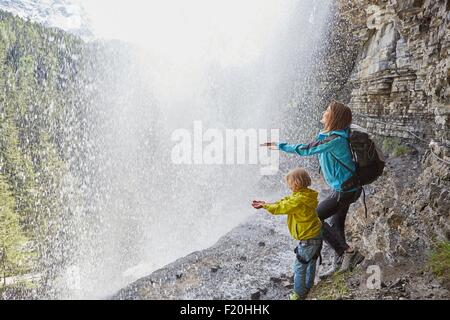 Mutter und Sohn, stehend unter Wasserfall, Hände zu spüren, das Wasser, die Sicht nach hinten Stockfoto