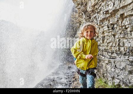 Junge Wandern unter Wasserfall, Lächeln Stockfoto