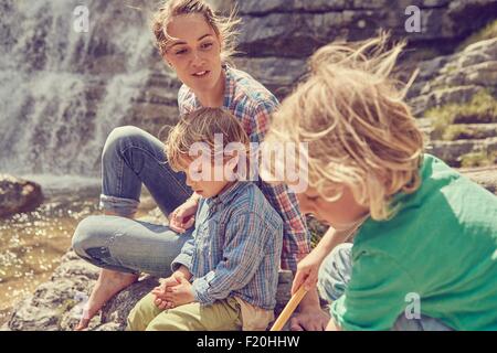 Mutter und Söhne, sitzen auf den Felsen von Wasserfall Stockfoto