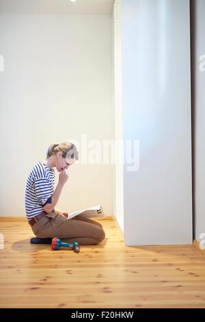 Reife Frau kniend und Lesen der Gebrauchsanweisung Flatpack Schrank Stockfoto