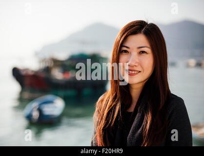 Porträt von Mitte Erwachsene Frau vor Boote auf dem Wasser, Blick auf die Kamera zu Lächeln Stockfoto