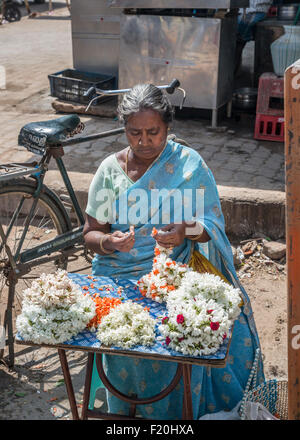 Alte Frau in einen blauen Sari machen Blumengirlanden für Angebote in der Hindu-Tempel in Chidambaram, Tamil Nadu, Indien Stockfoto