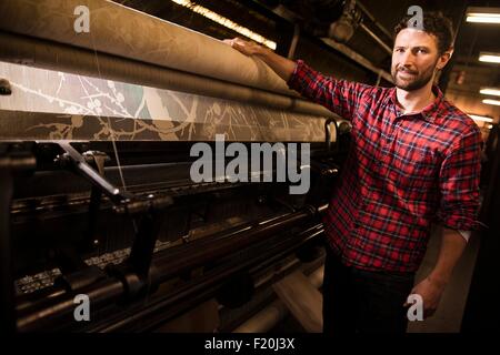 Porträt von männlichen Weaver neben alten Webmaschine in Textilfabrik Stockfoto