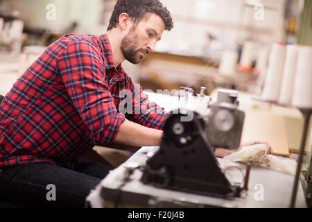 Männliche Weber mit Nähmaschine in alten Textilfabrik Stockfoto