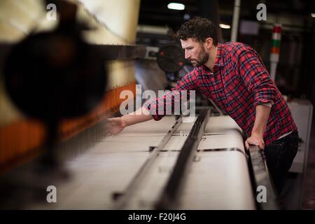 Junge männliche Weberin mit alten Webmaschine in Textilfabrik Stockfoto