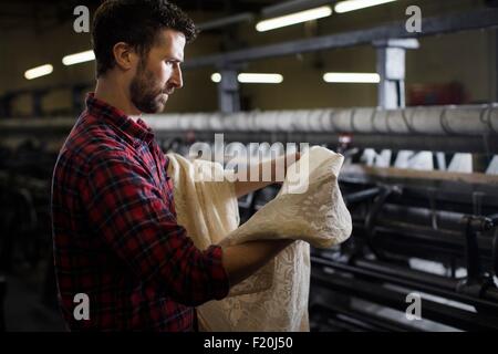 Porträt von männlichen Weaver Prüfung Lace von alten Webmaschine in Textilfabrik Stockfoto