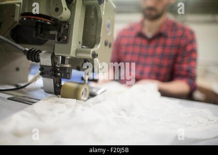 Männliche Weber Nähen Spitze auf Nähmaschine im alten Textilfabrik Stockfoto