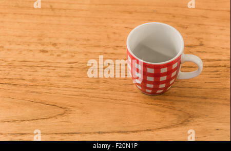 eine leere rot-weiß gestreiften Kaffeetasse über einen hölzernen Tisch Stockfoto