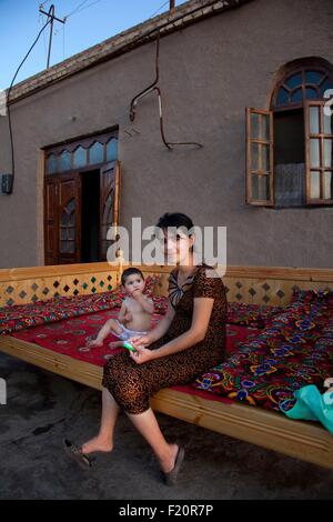 Usbekistan, Chiwa, Altstadt Itchan Kala, aufgeführt als Weltkulturerbe der UNESCO, eine Mutter mit ihrem Sohn in einem Sofa-Bett im Freien sitzen Stockfoto