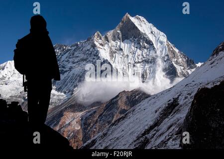 Nepal, Gandaki, Annapurna Region, Lawine auf dem Heiligen Berg Machapuchare angesehen vom Annapurna Base Camp, Silhouette ein Trekker im Vordergrund Stockfoto