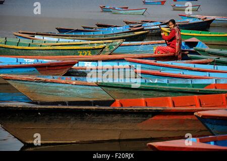 Nepal, Pokhara, Frau in rot unter der bunten hölzernen Boote auf th See Phewa Tal Stockfoto