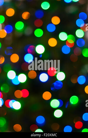 Einen hellen mehrfarbigen Bokeh Hintergrund erstellt durch eine Reihe von de-fokussierten Weihnachtsbeleuchtung auf einem Baum. Stockfoto