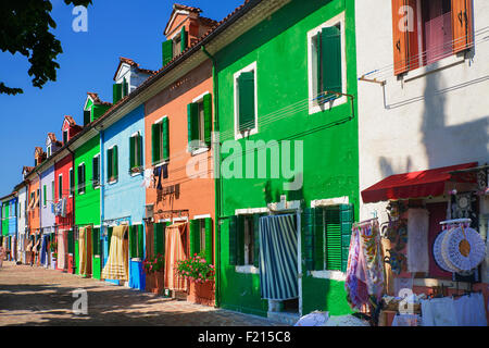 Italien, Veneto, Insel Burano, bunte Reihe von Hausfassaden mit Outdoor-Display der Spitze zu verkaufen. Stockfoto