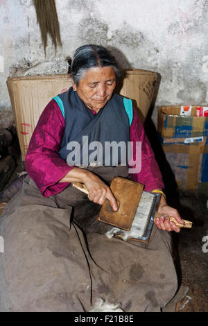 Indien West Bengal Darjeeling Senior tibetische Frau in traditioneller Kleidung Kardieren Schafe Wolle in tibetischen Flüchtlingslagern Selbsthilfe Stockfoto