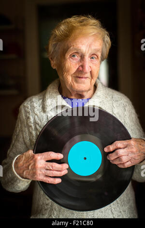 Alte Frau steht im Haus der Vinyl-Platte in den Händen hält. Stockfoto