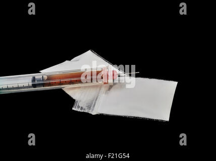 Heroin in einer Injektionsnadel mit Pakete von Heroin Pulver isoliert auf schwarz Stockfoto