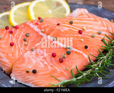Roher Lachs Fisch-Filet mit Zitronensaft, Gewürzen und frischen Kräutern auf Platte Stockfoto