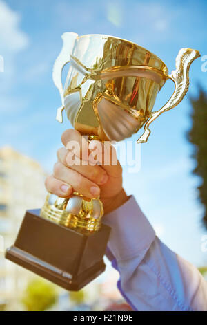 Hand der Geschäftsmann hält Goldschale Stockfoto