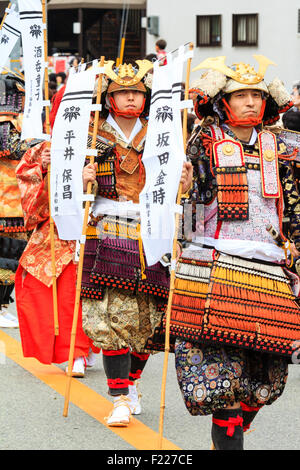 Genji Festival Parade in Japan. Japanische Männer verkleidet als Samurai in voller Rüstung, marschieren entlang der Hauptstraße, alle Banner. Stockfoto