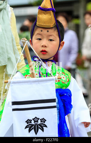 Genji Tada Heiligtum Festival. Parade, junge Kind, 6-8 Jahre alt, in Heian Ära Kostüm gekleidet, mit goldenen Hut, weißes Gewand und grüne Jacke, Auge - Kontakt. Stockfoto