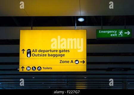 Gelbe Abfahrt Zeichen und grüne Notausgang melden Sie sich an der Abfahrt Halle von Heathrow International Airport, London Stockfoto