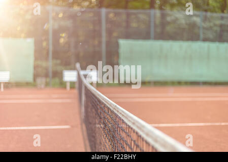 Blick über die gesamte Länge des Netzes auf ein Allwetter-Tennisplatz gegenüber Seite Fechten mit Werbung, Gericht der konzeptionellen leer Stockfoto