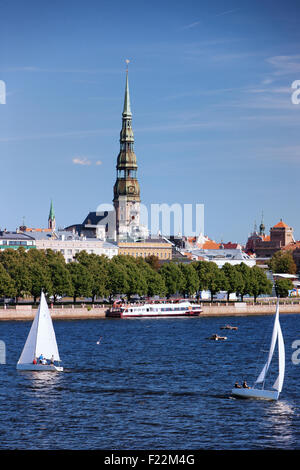 Lettland. Yachten mit Segel und einem Ausflugsschiff auf dem Fluss Daugava im Hintergrund Panorama mit Kirchturm in Riga Stockfoto