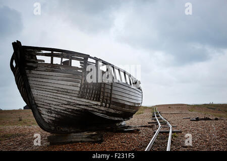 Verlassene Holzboot gestrandet auf die Schindel in der Nähe von alten Schmalspur-Schienen. Stockfoto