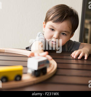 Kleiner Junge spielt mit einer Holzeisenbahn. Stockfoto